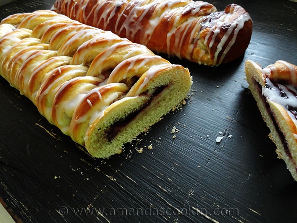 A close up photo of braided blackberry breakfast Danishes with a slice missing off of one.