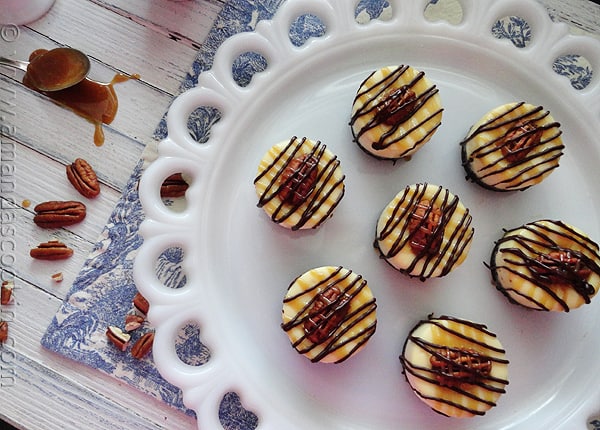 An overhead photo of mini turtle cheesecakes resting on a white decorative platter.