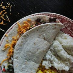 An overhead photo of a steak soft taco resting on a plate.