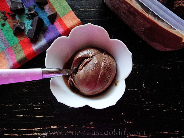 An overhead photo of a scoop of black cow ice cream with a spoon in a decorative bowl.