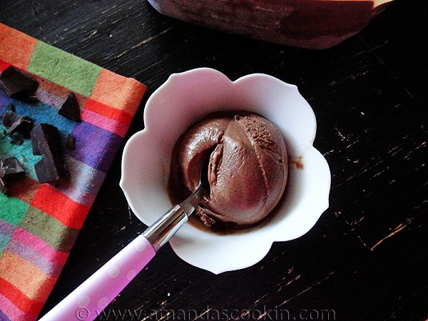 An overhead photo of a scoop of black cow ice cream in a decorative bowl with a spoon.