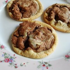 A close up photo of three double stack chocolate chip cookies resting on a plate.