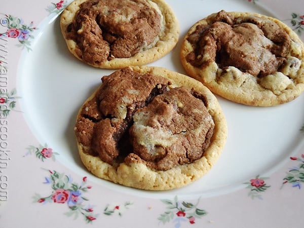 A close up photo of three double stack chocolate chip cookies resting on a plate.