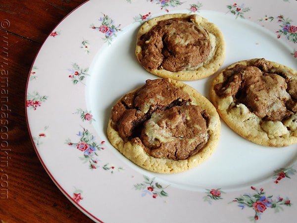 A photo of three half and half chocolate chip cookies resting on a plate.