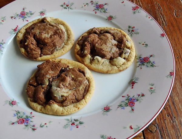 A photo of three half and half chocolate chip cookies resting on a plate.