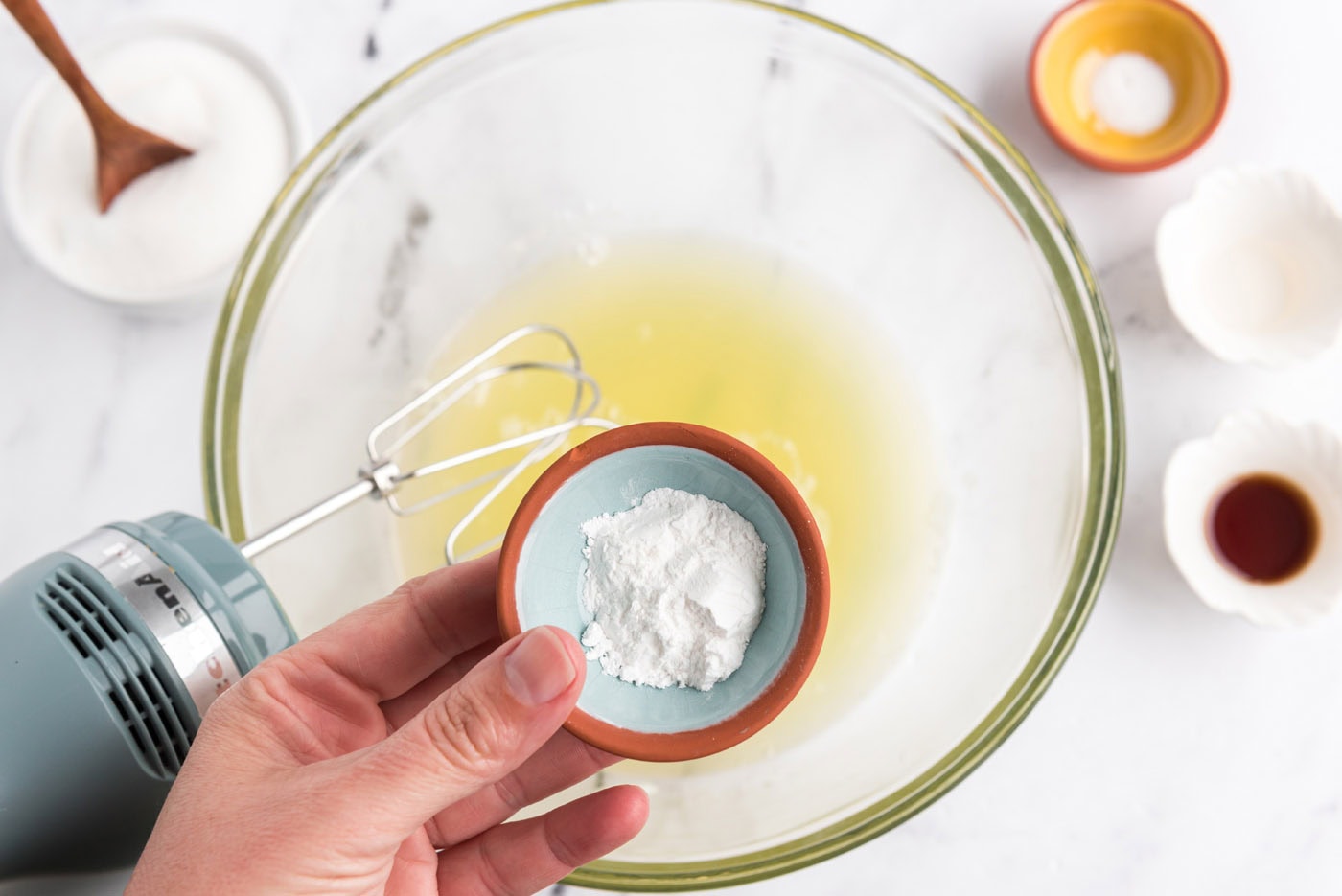 adding cream of tartar to egg whites in a bowl