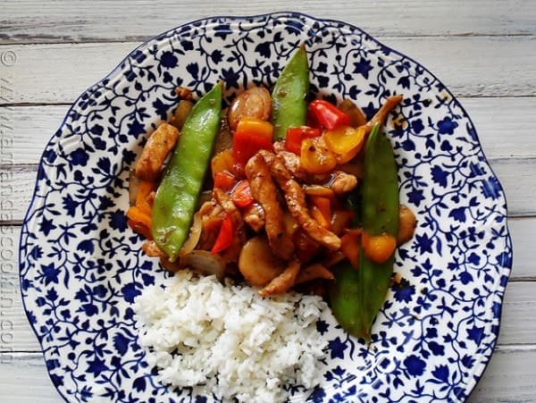 An overhead photo of a plate of peppered pork stir fry with sweet peppers with rice on the side.