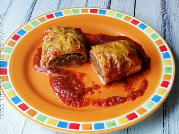 A photo of a Taco Bell enchirito copycat cut in half resting on a plate.