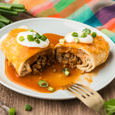 A close up photo of a Taco Bell enchirito copycat cut in half resting on a plate.