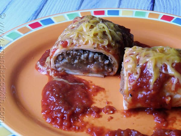 A close up photo of a Taco Bell enchirito copycat cut in half resting on a plate.