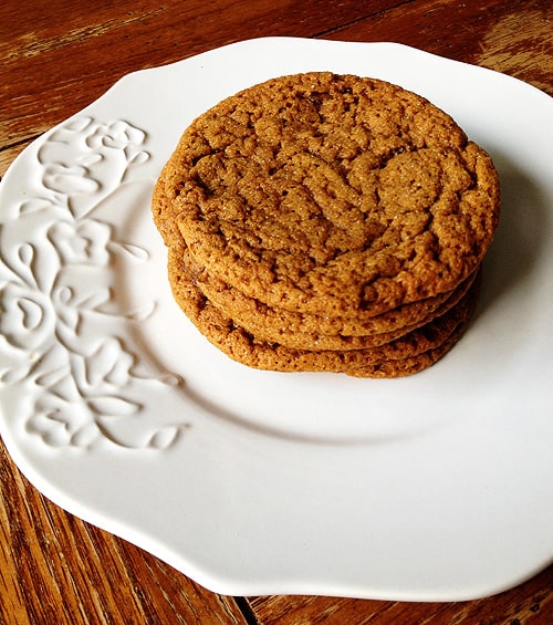 A stack of sugar topped molasses spice cookies on a white plate.