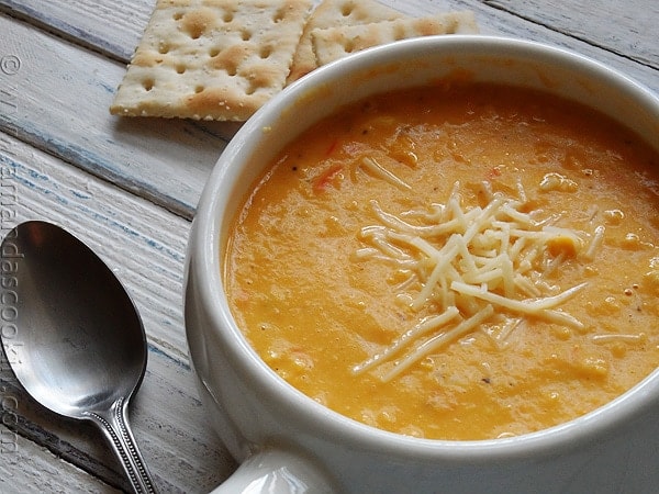 A close up photo of a bowl of creamy white cheddar corn soup.