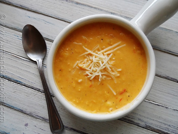 A close up photo of a bowl of creamy white cheddar corn soup.