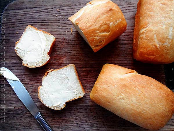 A photo of sliced Amish white bread mini loaves on a wooden cutting board.