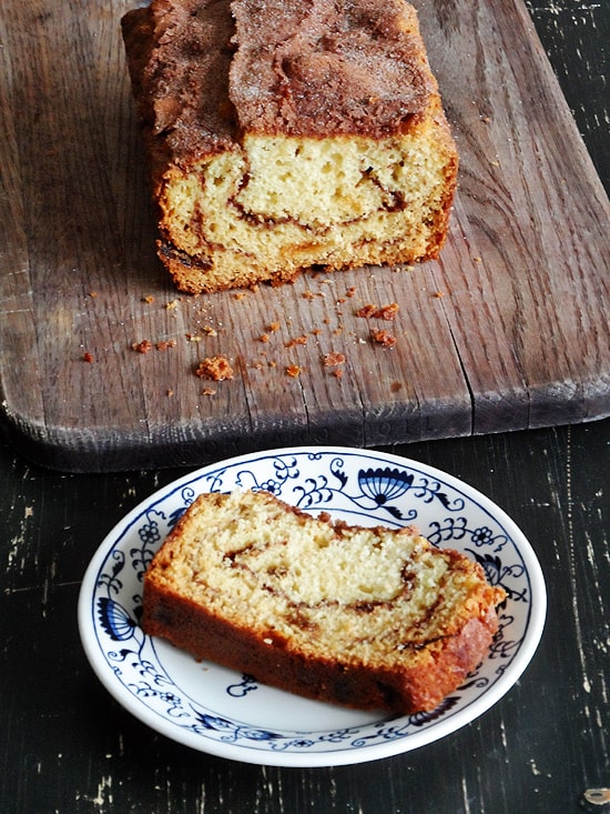 An overhead photo of a loaf of cinnamon raisin swirl quick bread on a wooden cutting board and a slice on a plate.