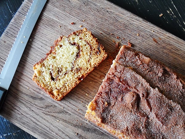 An overhead photo of a loaf of sliced cinnamon raisin swirl quick bread on a wooden cutting board.