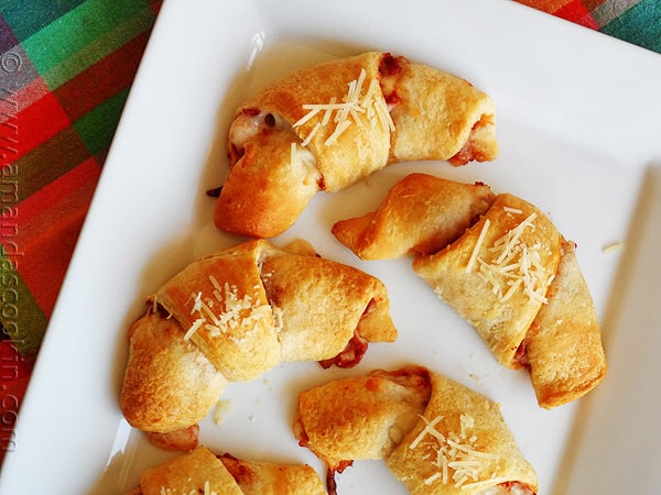 An overhead close up photo of pizza crescent roll ups on a white platter.