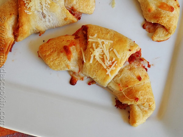 A close up overhead photo of a pizza crescent roll up on a white platter.
