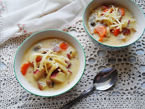 A photo of two bowls of rustic garlic potato soup.