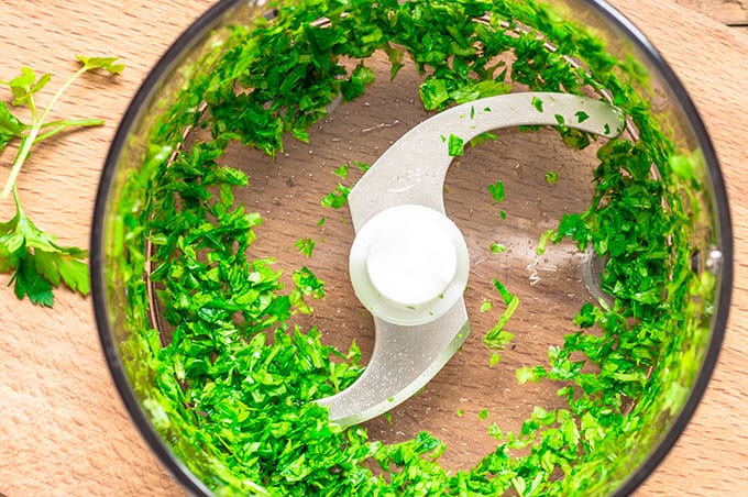 An overhead photo of cilantro chopped in a food processor. 