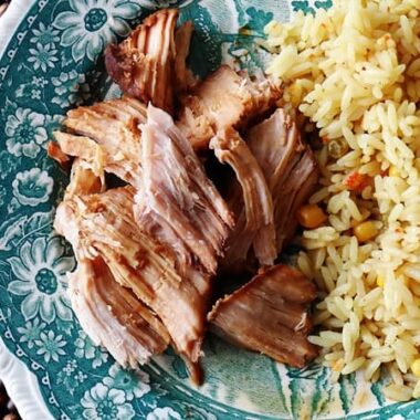 A close up overhead photo of slow cooker oriental pork roast on a plate next to rice.