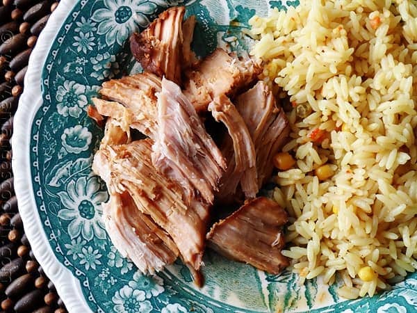 A close up overhead photo of slow cooker oriental pork roast on a plate next to rice.