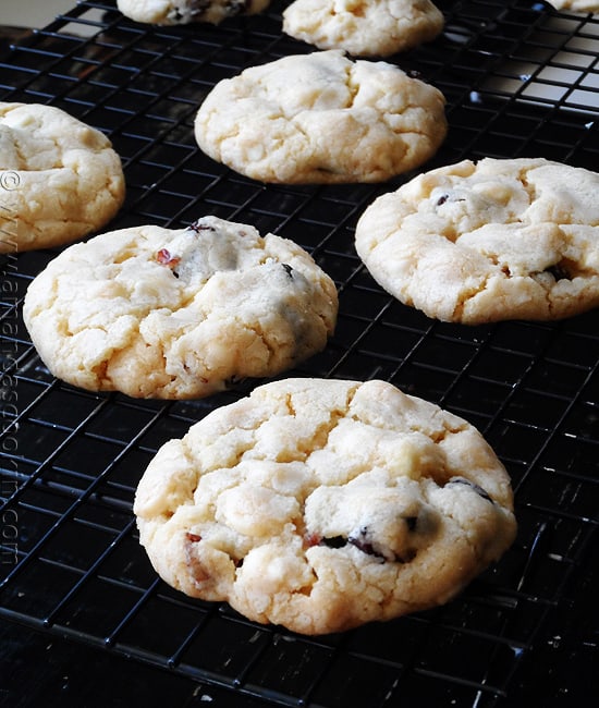A close up photo of cherry white chocolate chip cookies resting on a cooling rack.