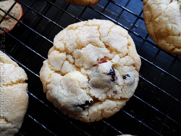 A close up overhead photo of a cherry white chocolate chip cookie on a cooling rack.