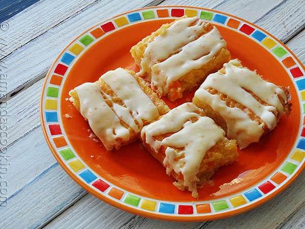 A close up photo of tropical dream dessert bars on an orange plate.