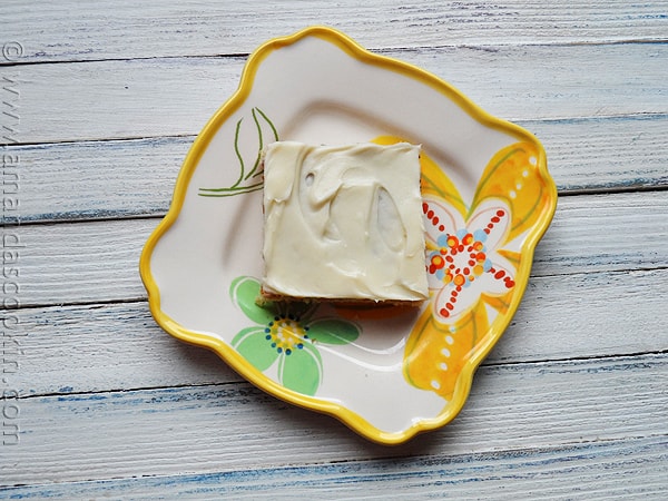 An overhead photo of a banana bar with vanilla cream cheese frosting on a plate.