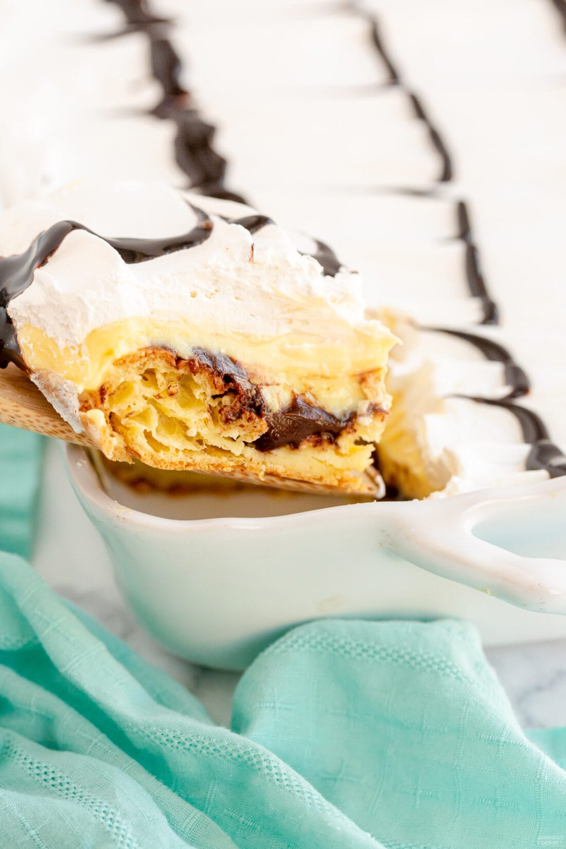 removing a slice of Cream Puff Chocolate Eclair Cake from pan