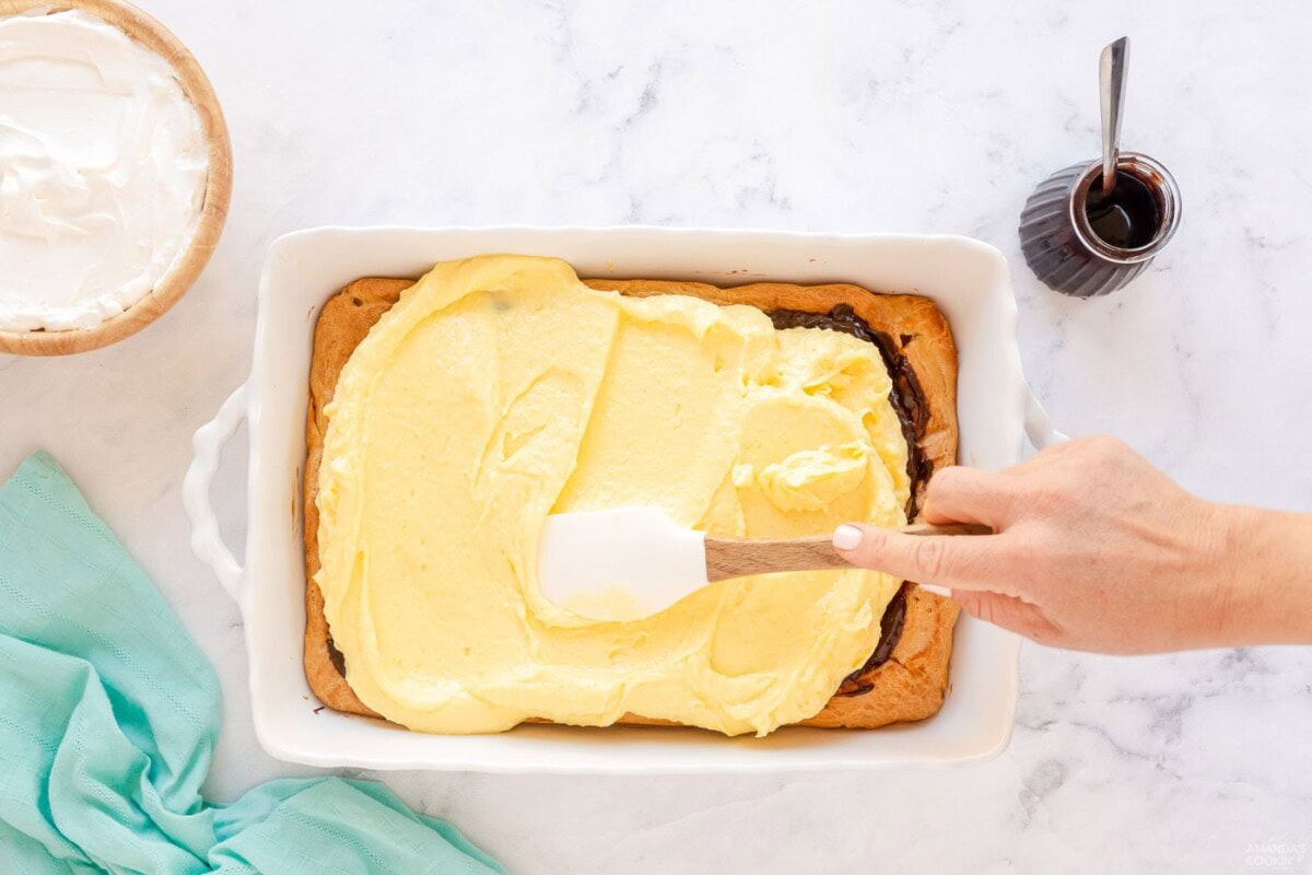 spreading pudding mixture on top of chocolate and puffy pastry