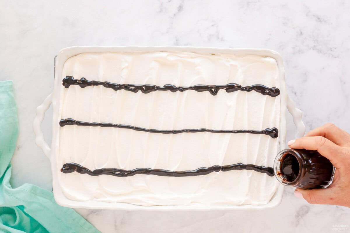 pouring lines of chocolate on top of cake