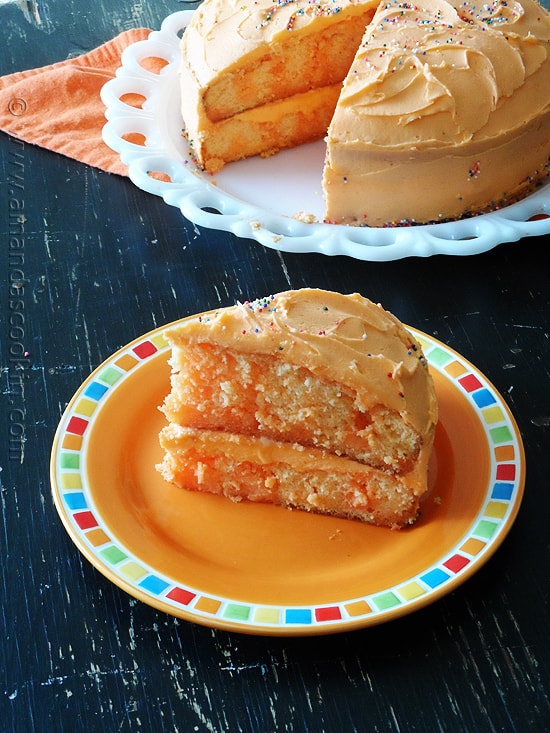 A photo of a slice of orange poke cake on an orange plate.