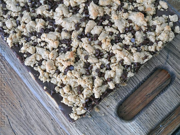 An overhead photo of peanut butter chocolate layer bars fresh out of the pan resting on a wooden cutting board.