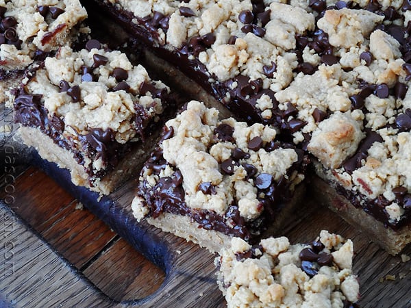 An overhead photo of peanut butter chocolate layer bars resting on a wooden cutting board.