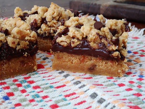 A close up photo of peanut butter chocolate layer bars resting on a multicolored napkin.