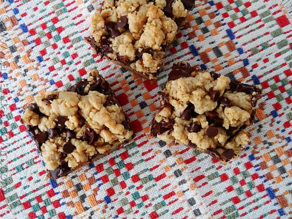 An overhead photo of three peanut butter chocolate layer bars resting on a multicolored napkin.