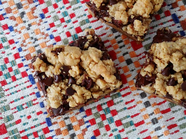 An overhead photo of peanut butter chocolate layer bars resting on a multicolored napkin.