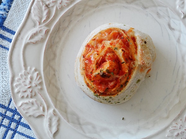 A overhead photo of a pizza roll up on a plate.