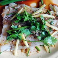 A close up photo of Chinese style parchment fish on a white plate topped with fresh cilantro.