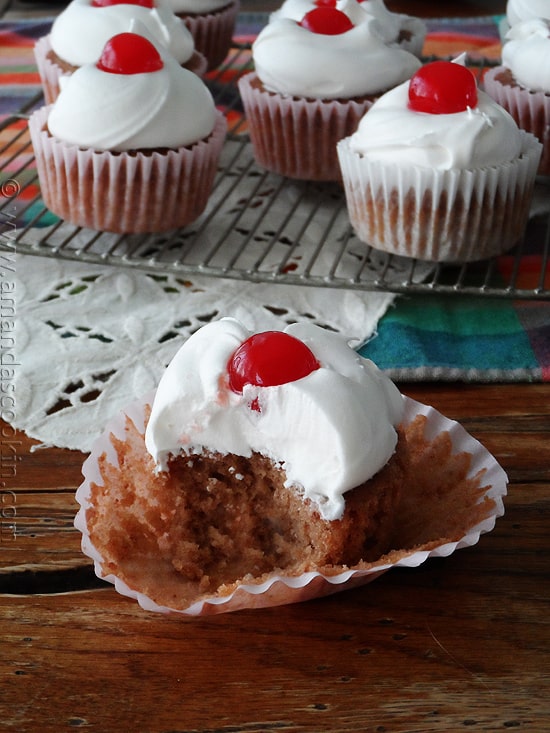 A close up photo of a half eaten cherry cupcake.