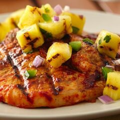 A close up photo of pork chops al pastor made on the grill.