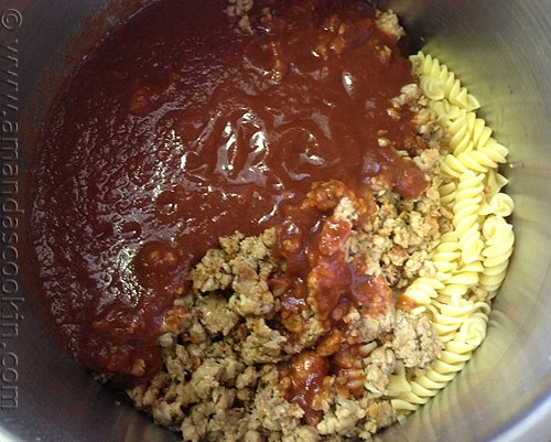 An overhead photo of a bowl of sausage, spaghetti sauce and pasta.