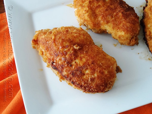 A close up photo of oven fried chicken breasts on a white plate.