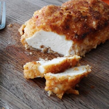 A close up photo of an oven fried chicken breast cut into slices.