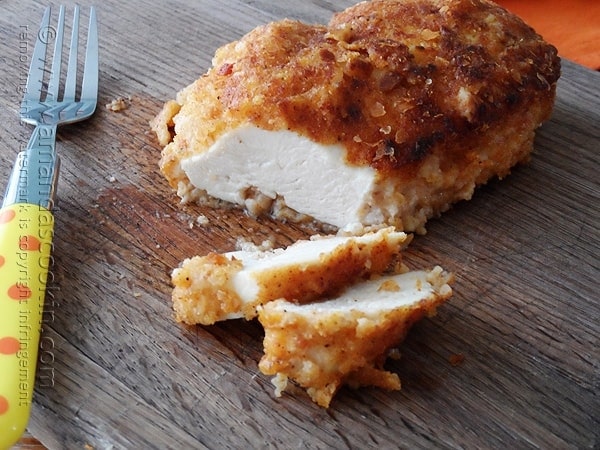 A close up photo of an oven fried chicken breast cut into slices.