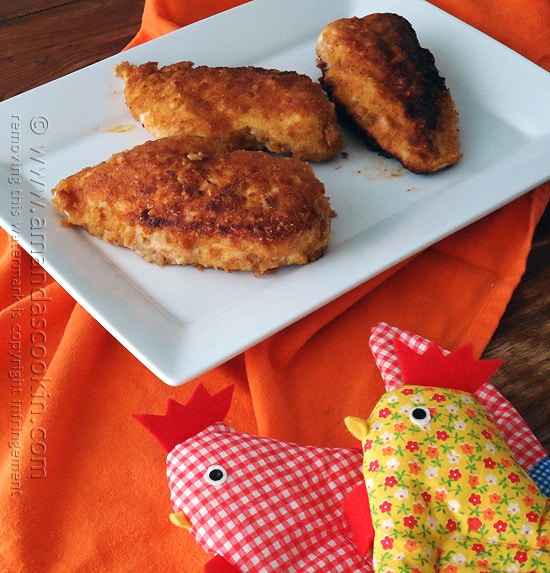 Three oven fried chicken breasts on a white plate.