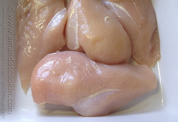 A close up photo of raw chicken breasts.