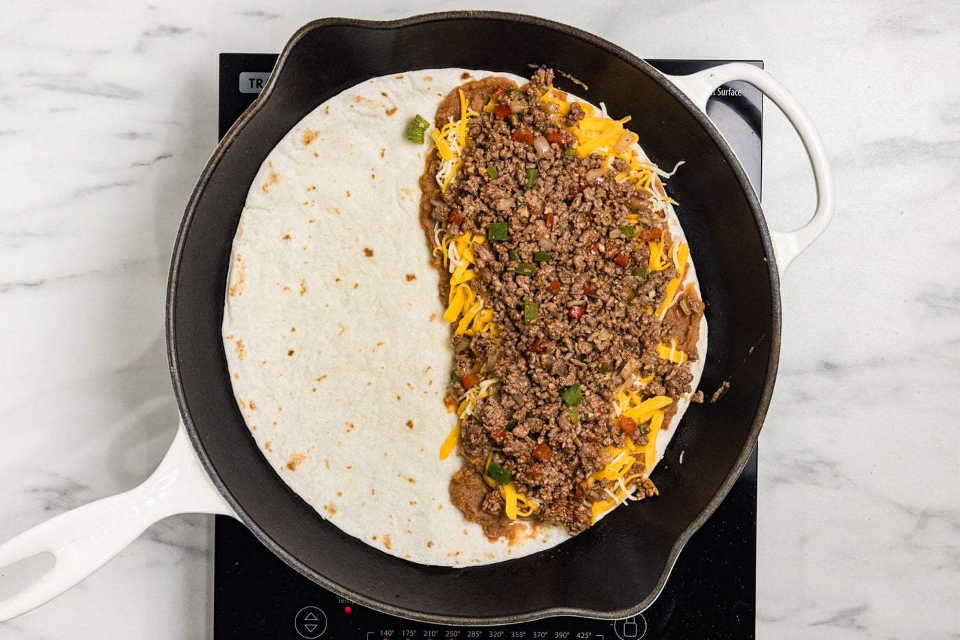 beans, cheese, and ground beef on tortilla